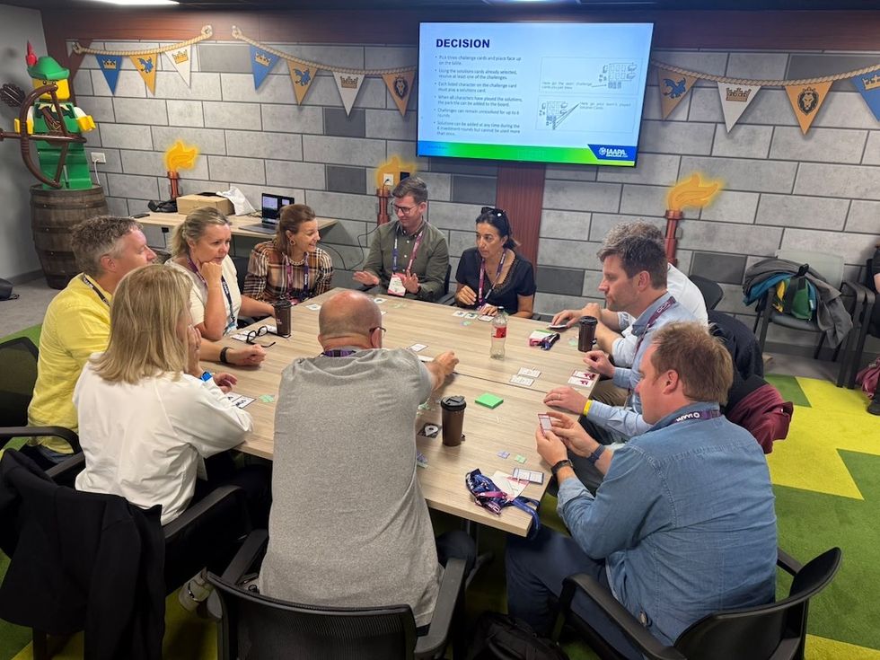 Group of people playing a card game around a table in a decorated room.