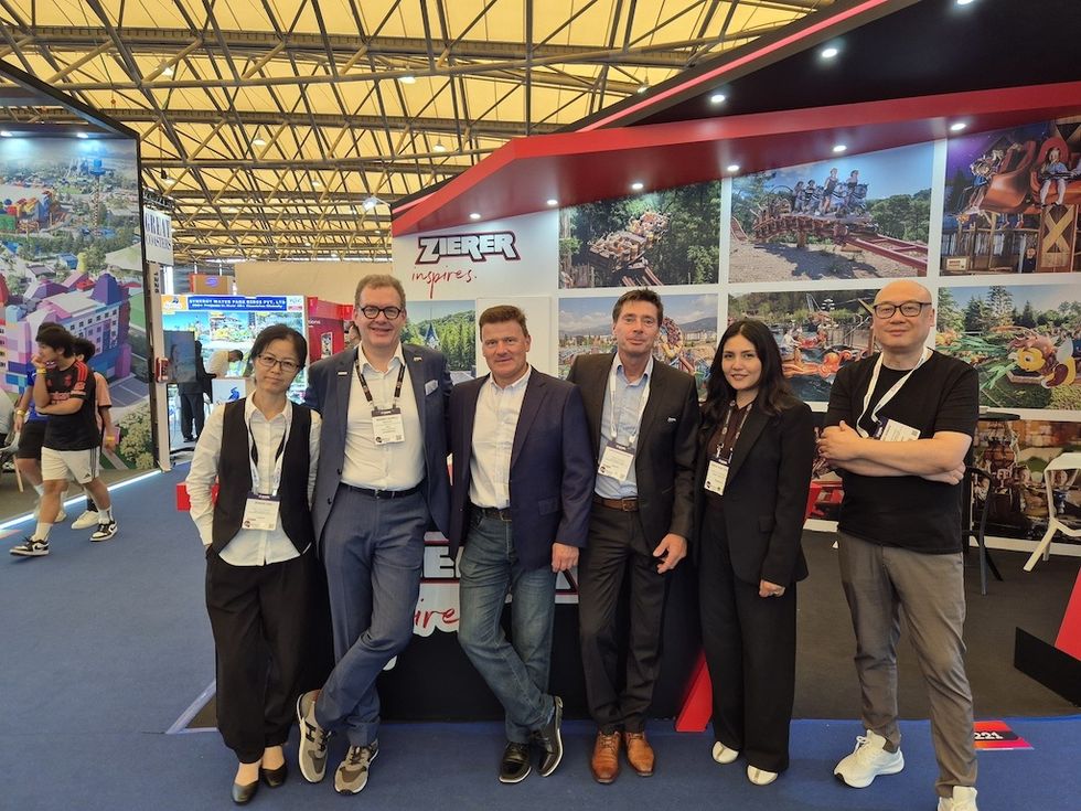Group of people posing at a trade show booth with colorful displays in the background.