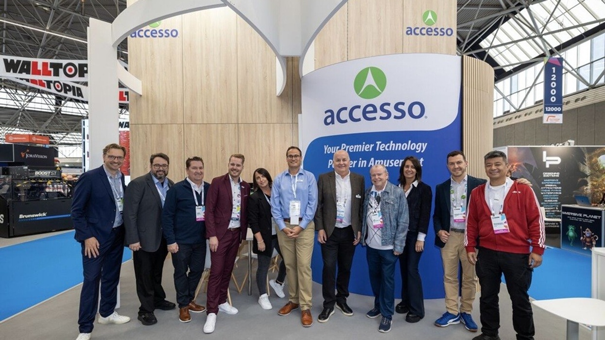 Group of people posing at the accesso booth in an exhibition hall at IAAPA Expo