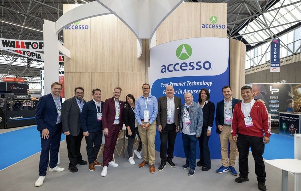 Group of people posing at the accesso booth in an exhibition hall at IAAPA Expo