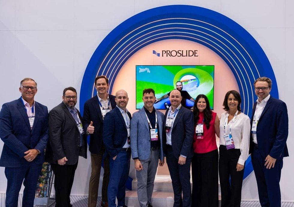 Group of people posing in front of a ProSlide display at a convention booth.