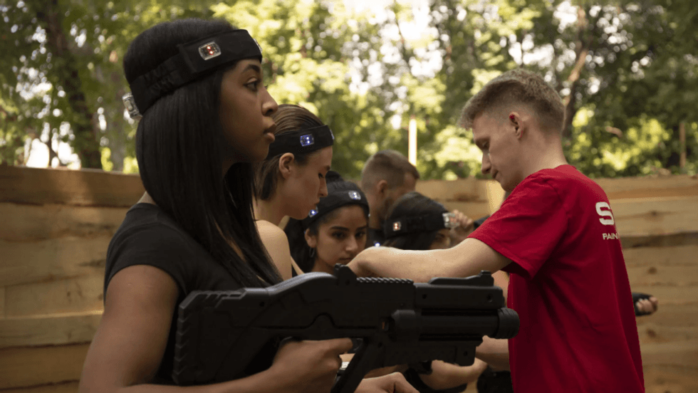 Group of people preparing for laser tag outdoors, wearing headbands and holding gear.