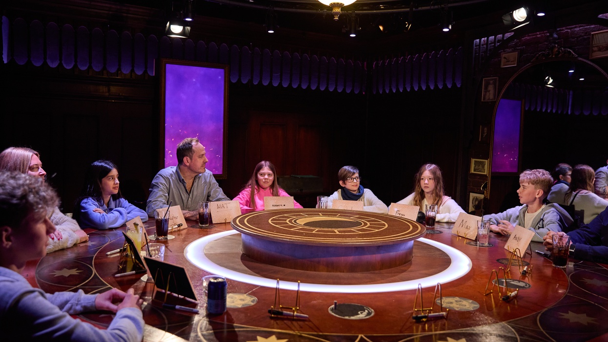 Group of people sit around a circular table with name cards and drinks.