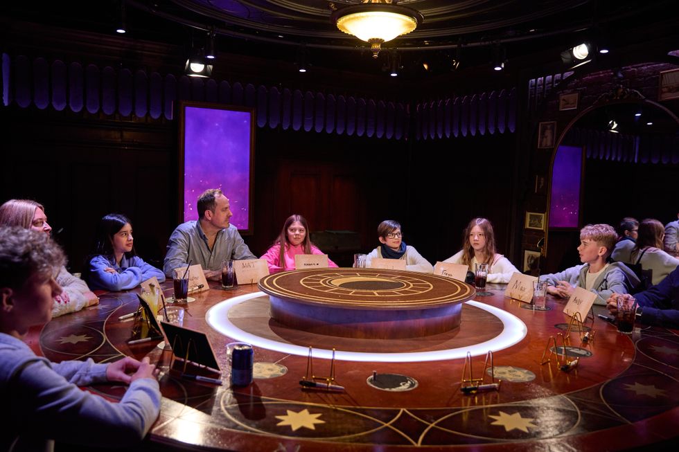 Group of people sit around a circular table with name cards and drinks.