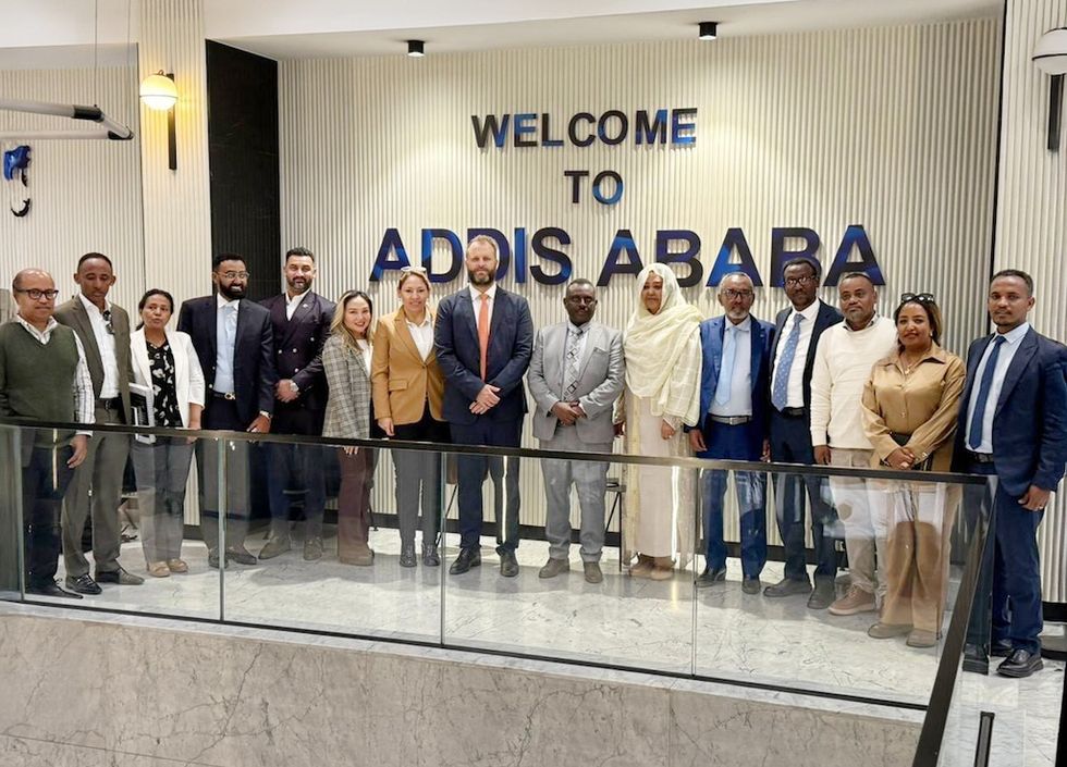 Group of people standing under "Welcome to Addis Ababa" sign indoors.