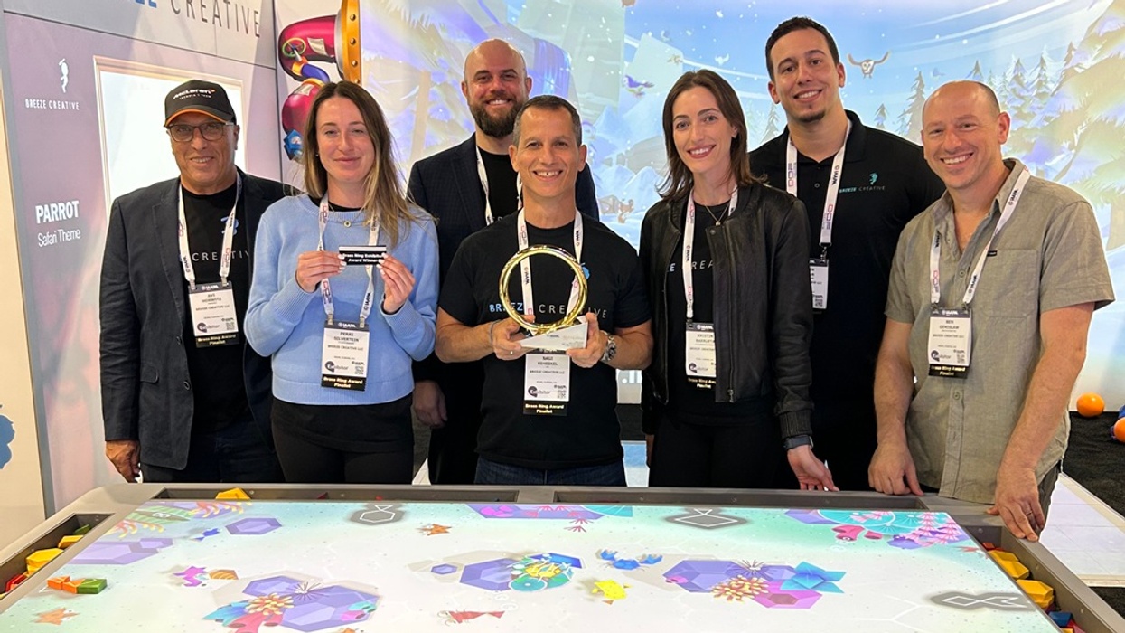 Group of seven people posing with awards at a colorful Breeze Creative booth.