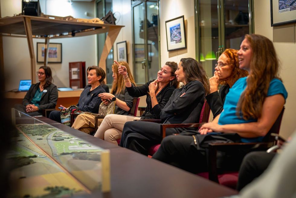 Group of women engaged in a presentation, seated and smiling in a conference room during Disneyland Paris mentorship scheme