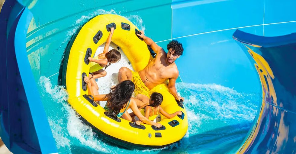 Group on a yellow raft enjoying a water slide at an aqua park called Knott's Soak City