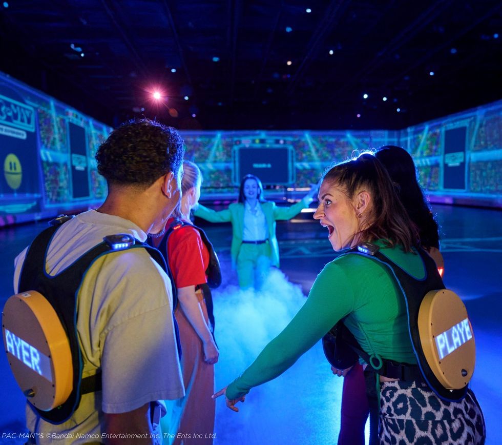 Group playing immersive Pac-Man game with glowing screens and fog.