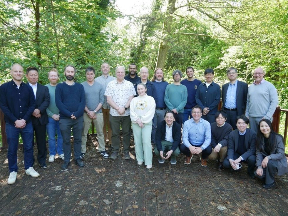 Group posing outdoors on a wooden deck, surrounded by trees.