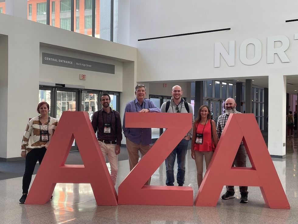 Group posing with large "AZA" letters in a bright indoor space.
