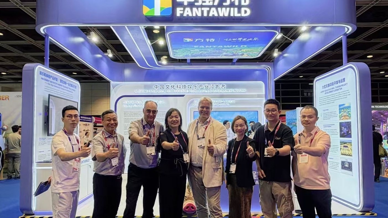 Group posing with thumbs up at a Fantawild exhibition booth.