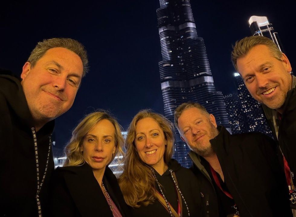 Group selfie at night with a skyscraper lit up in the background.