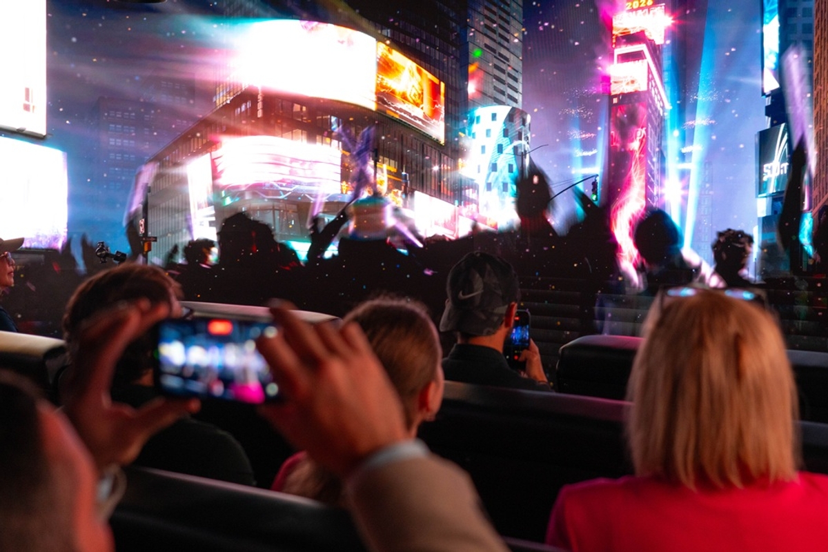 Group watching vibrant screens and lights in a crowded city setting at night in the Times Travel experience.