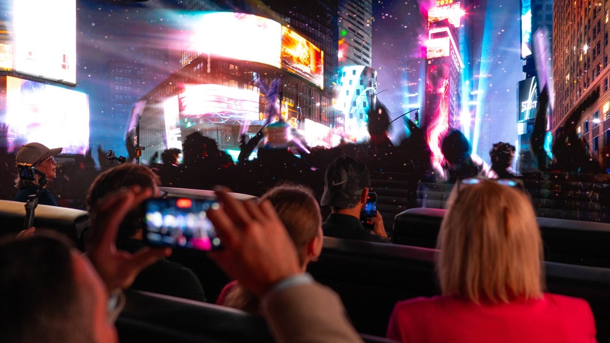 Group watching vibrant screens and lights in a crowded city setting at night in the Times Travel experience.