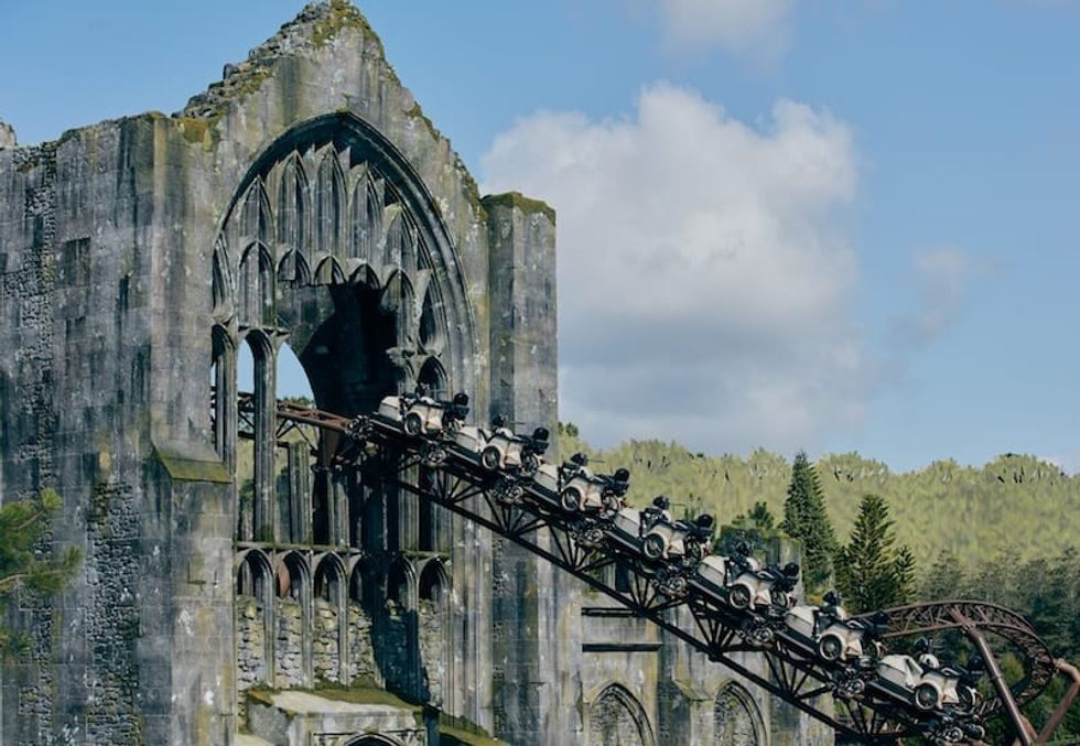 Hagrid\u2019s Magical Creatures Motorbike Adventure passes through a gothic stone arch with lush forest in the background.