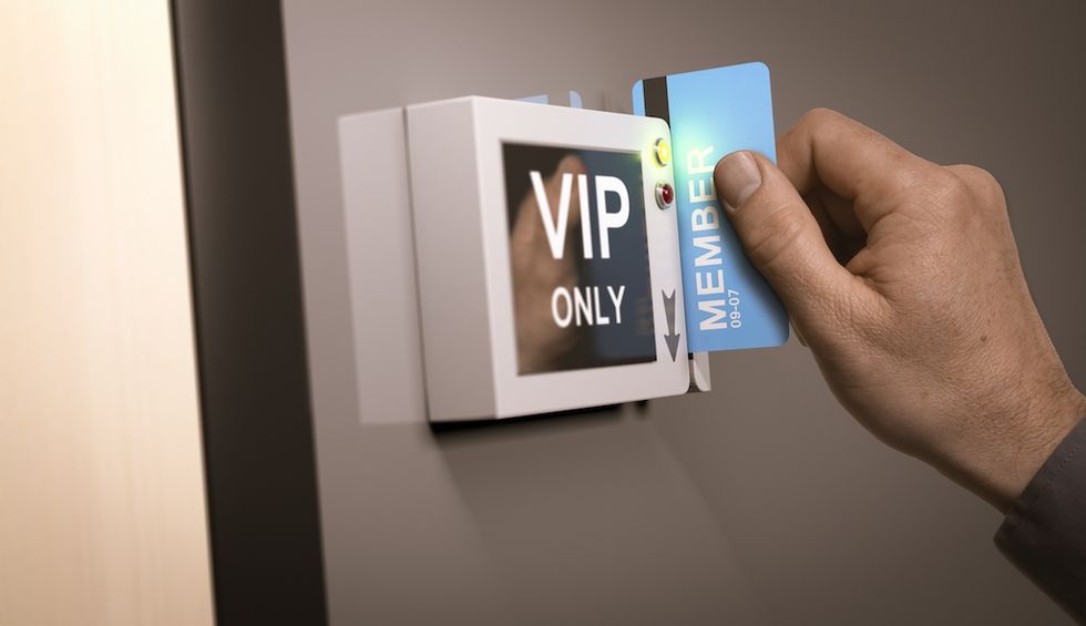 Hand swiping a blue member card through a "VIP Only" access reader.