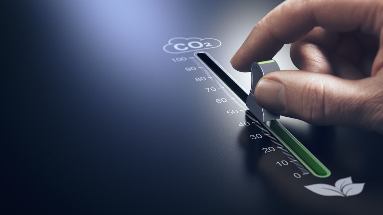 Hand using a slider to reduce CO2 emissions. Carbon free energy. Concept of decarbonization.