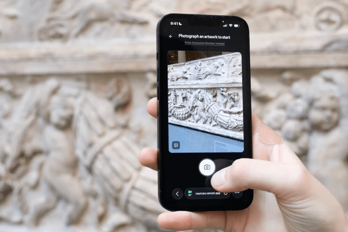 Hand using a smartphone app to photograph ornate stone artwork at the Met museum