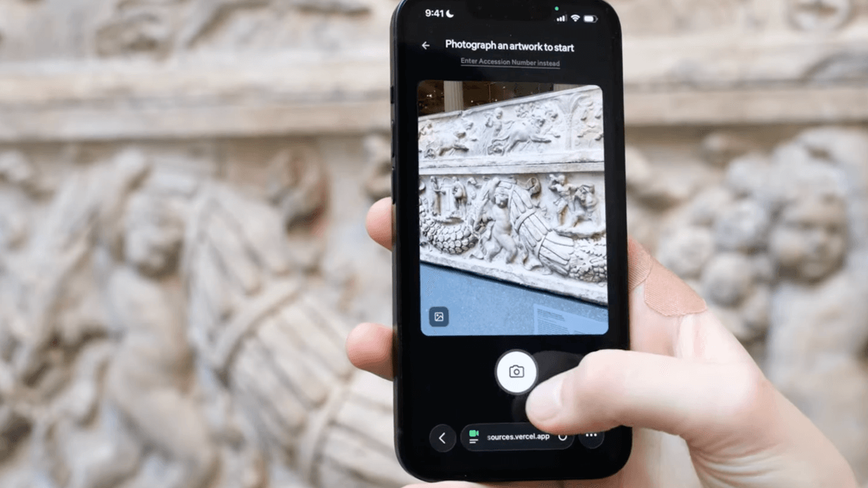 Hand using a smartphone app to photograph ornate stone artwork at the Met museum
