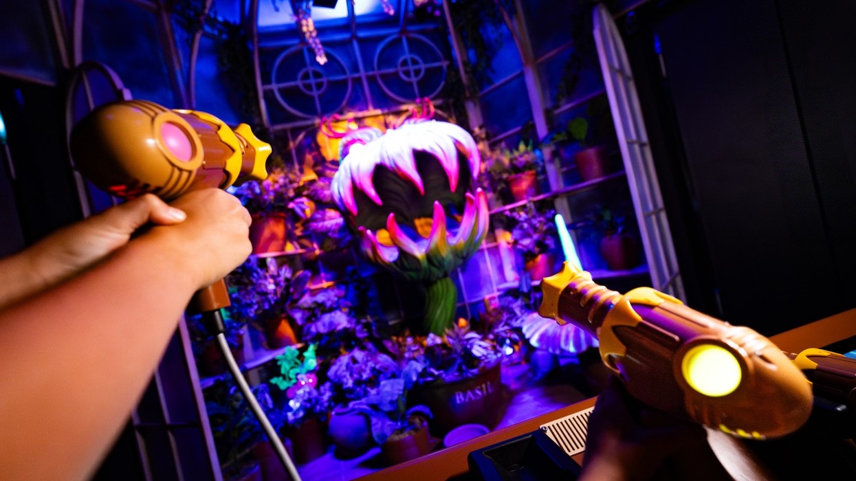 Hands aiming toy guns at a glowing, giant plant in a neon-lit room.