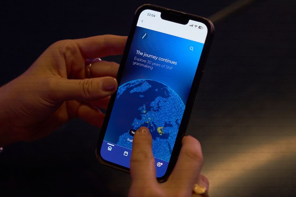 Hands holding a smartphone showing an app about SNF grantmaking.