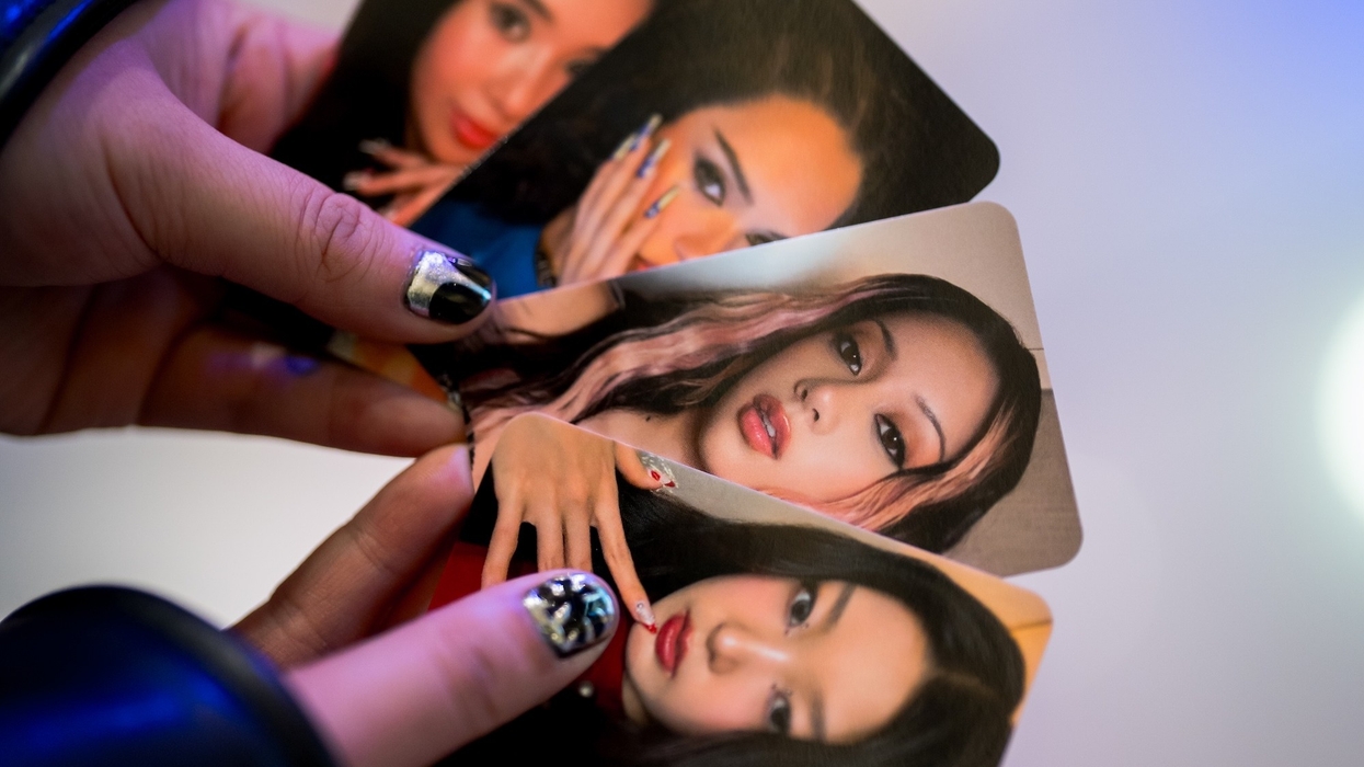 Hands holding four glossy photo cards of women with styled nails