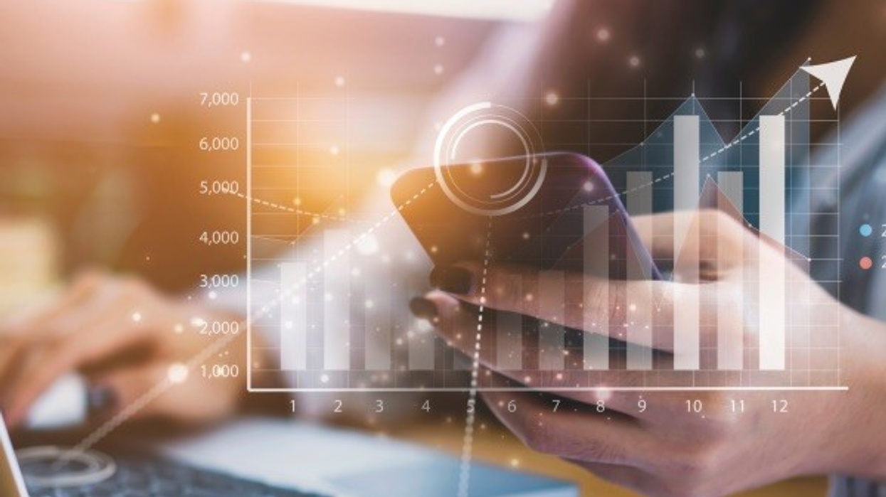 Hands using a smartphone and laptop with an overlay of rising bar and line graphs.