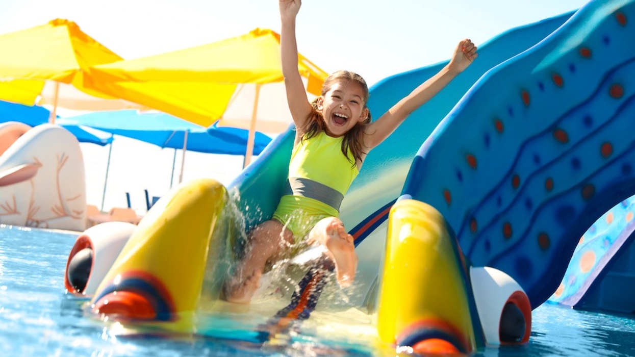 Happy girl on slide at water park. Summer vacation
