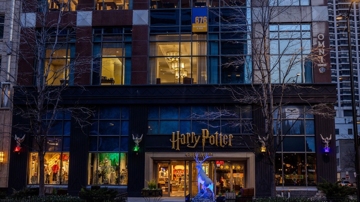 Harry Potter store entrance with lit stag statue and colorful lights on city street.