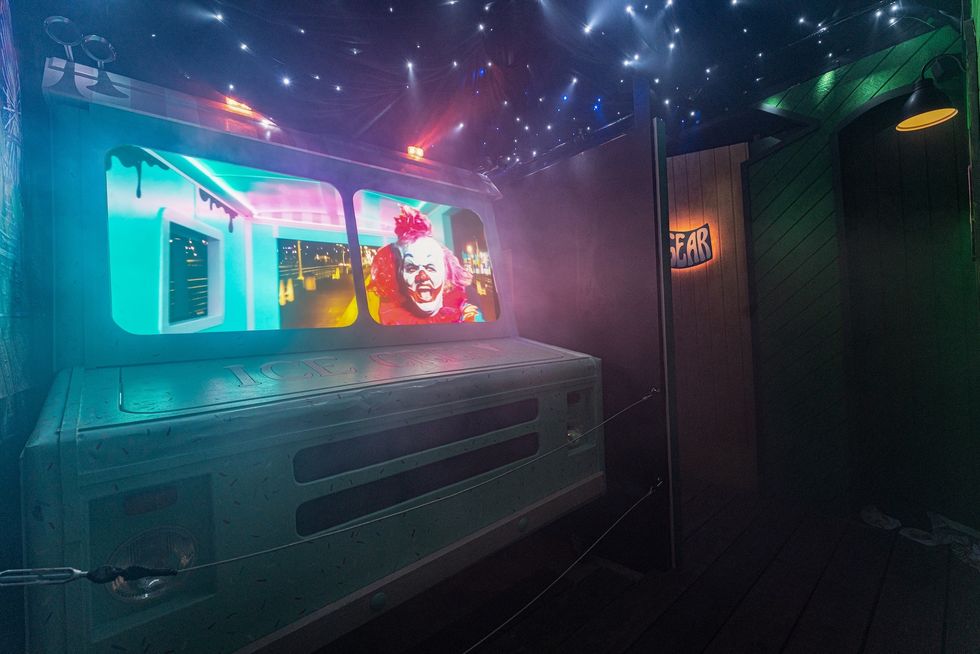 Haunted ice cream truck with clown under starry lights and eerie glow.