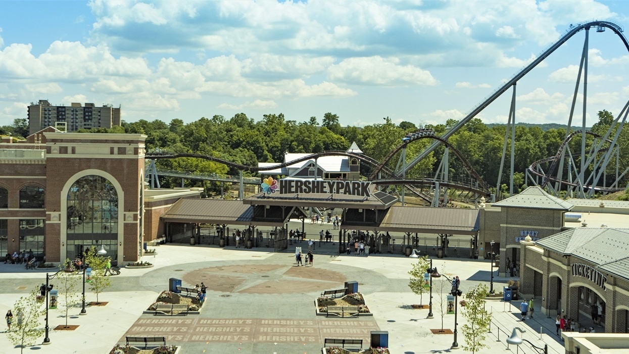 Hersheypark entrance with roller coaster and buildings on a sunny day.