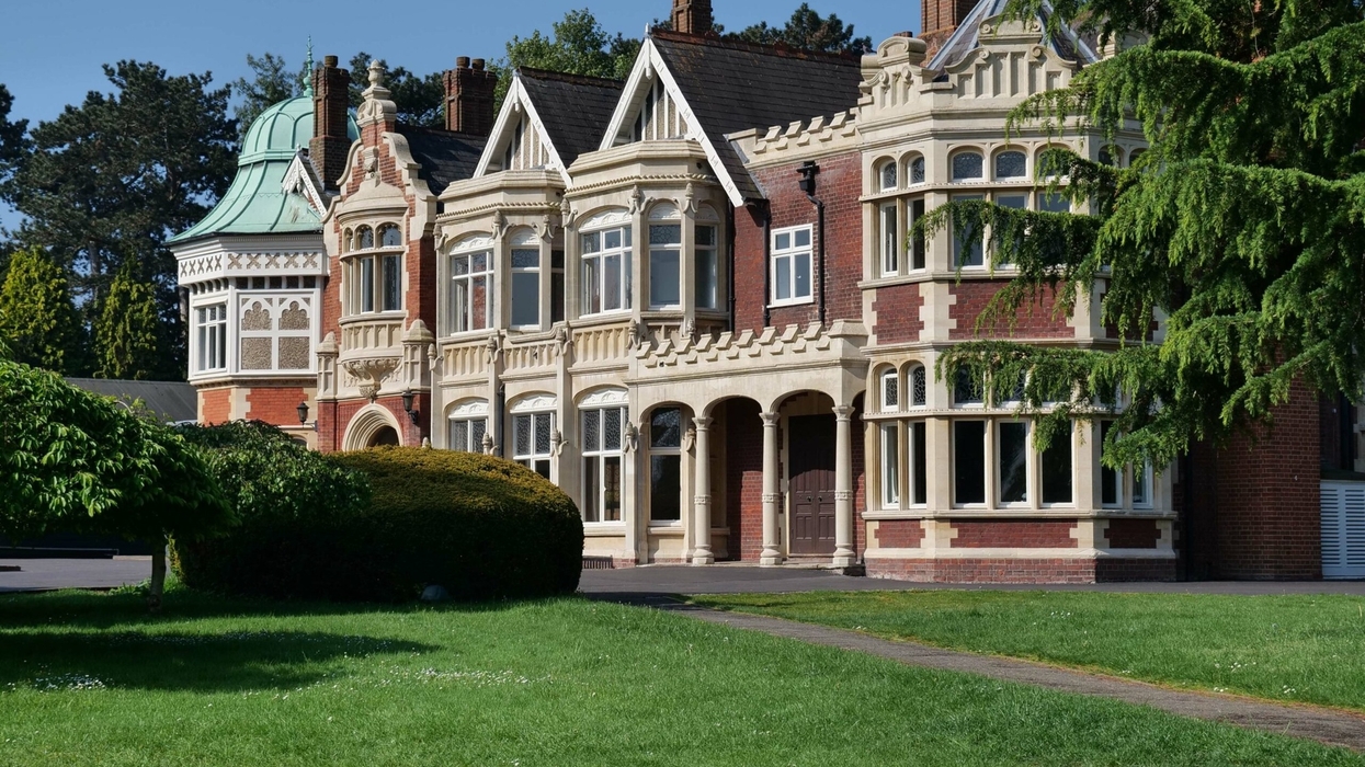 Historic Bletchley Park Mansion with ornate windows, green dome, and manicured lawn.