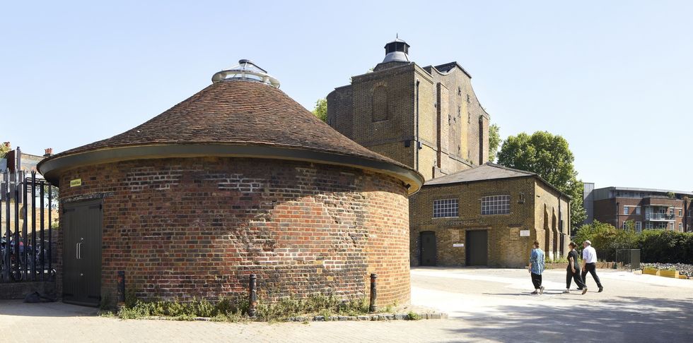 Historic brick buildings of the Quentin Blake Centre for Illustration with roundhouse; people walking past on a sunny day.