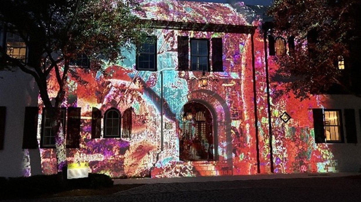 Historic building facade lit up by colorful, intricate light projections at night.