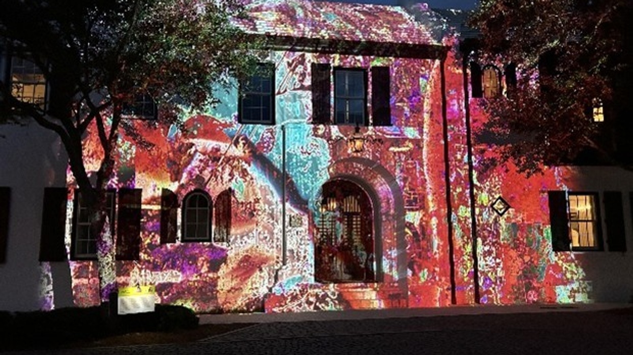 Historic building facade lit up by colorful, intricate light projections at night.