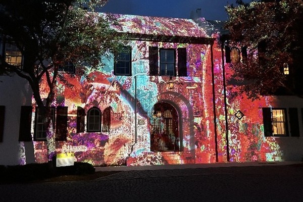 Historic building facade lit up by colorful, intricate light projections at night.