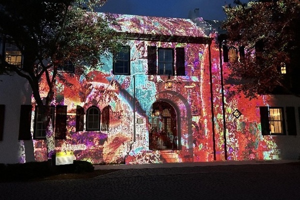 Historic building facade lit up by colorful, intricate light projections at night.