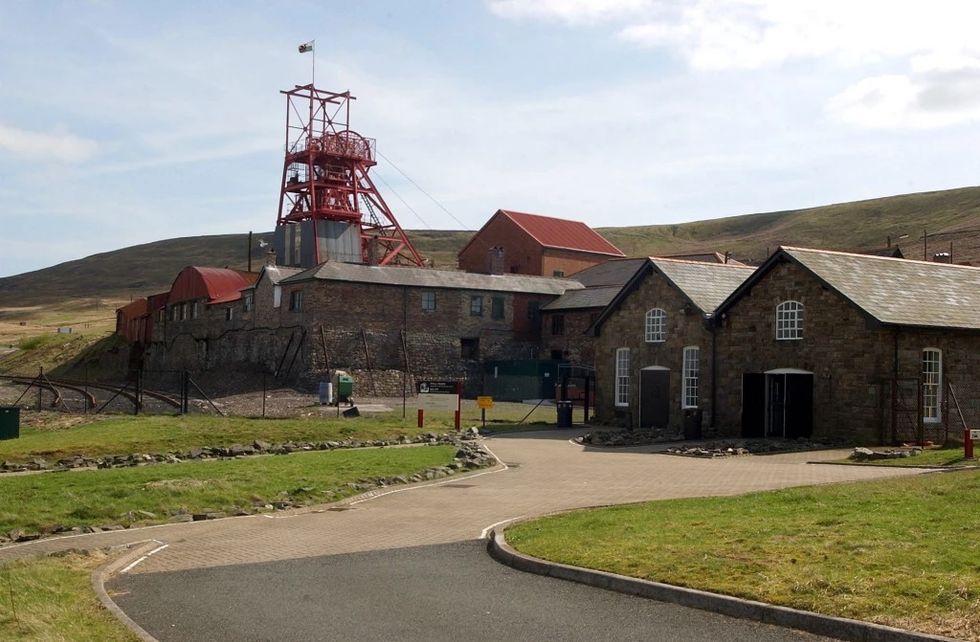 Historic mine buildings with red metal structures in a hilly landscape at Big Pit National Coal Museum