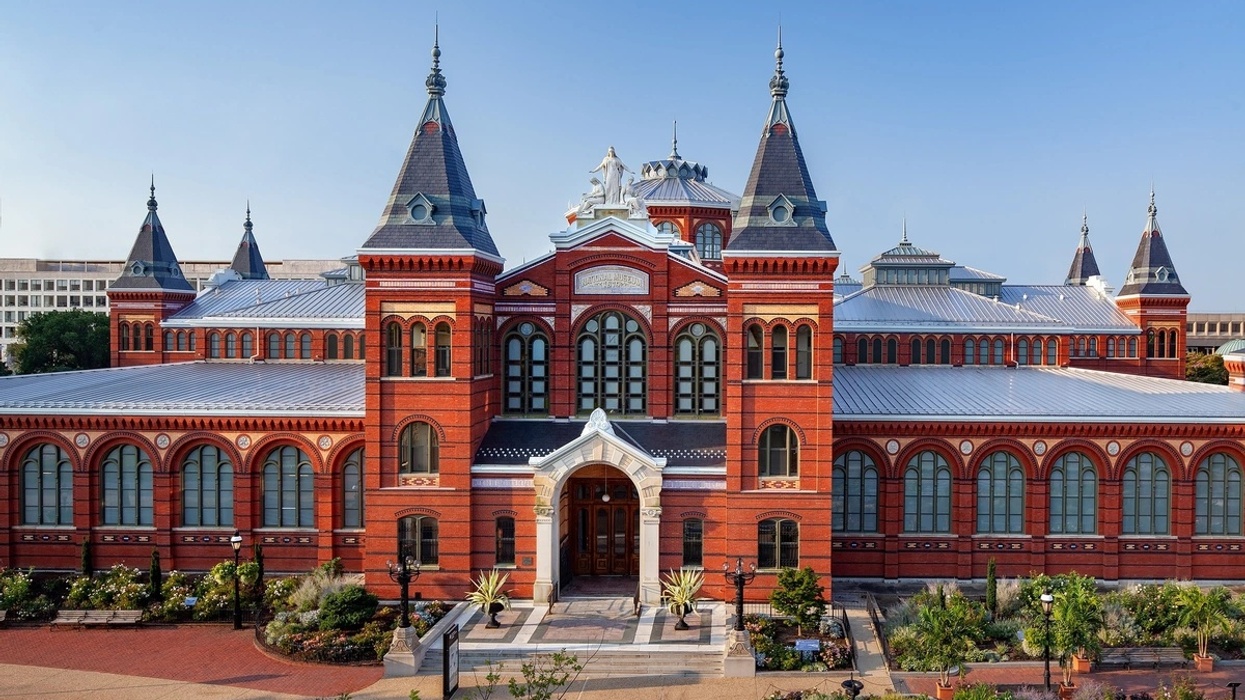 Historic red brick Arts and Industries Building with towers and arched windows under a clear blue sky.