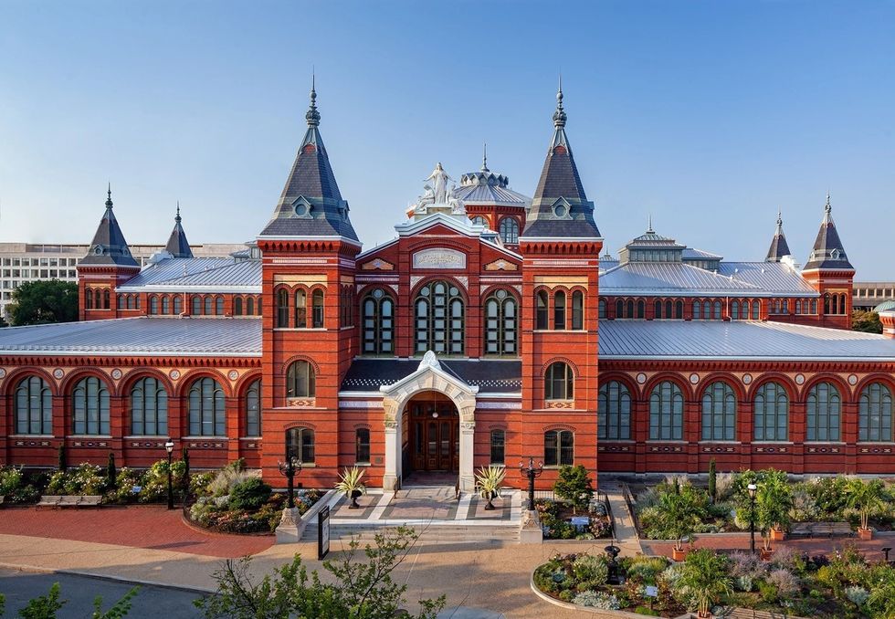 Historic red brick Arts and Industries Building with towers and arched windows under a clear blue sky.