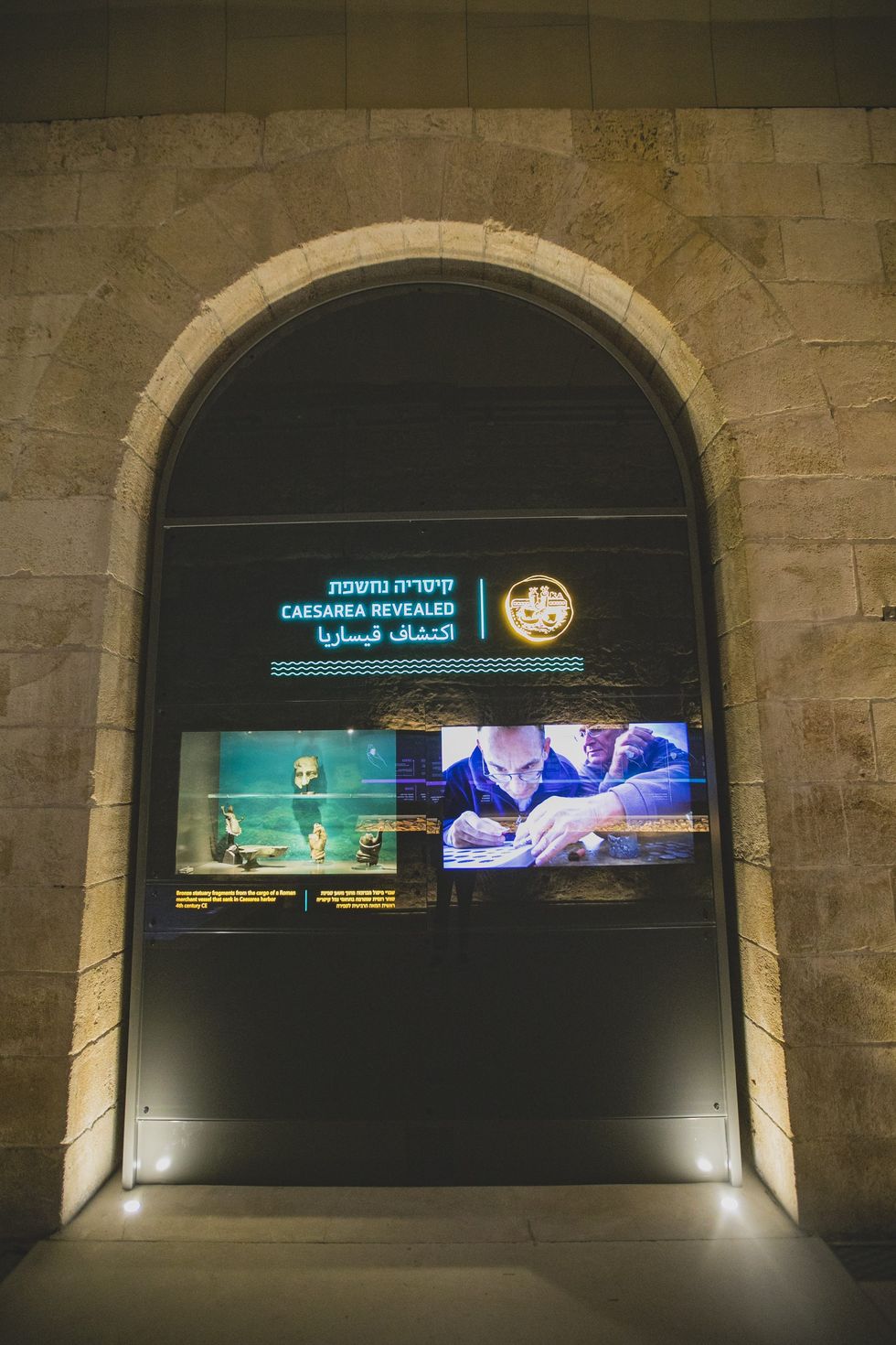 Illuminated archway display of "Caesarea Revealed" exhibition with images and text at Caesarea Harbour Visitor Centre