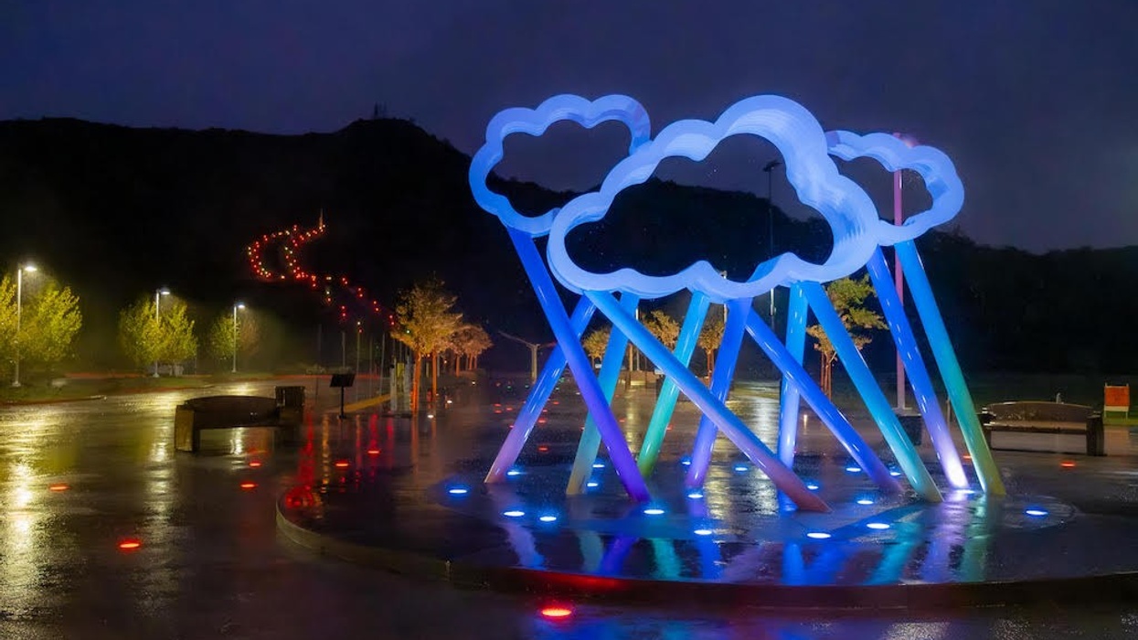 Illuminated cloud sculpture with colorful lights at night in a park setting.