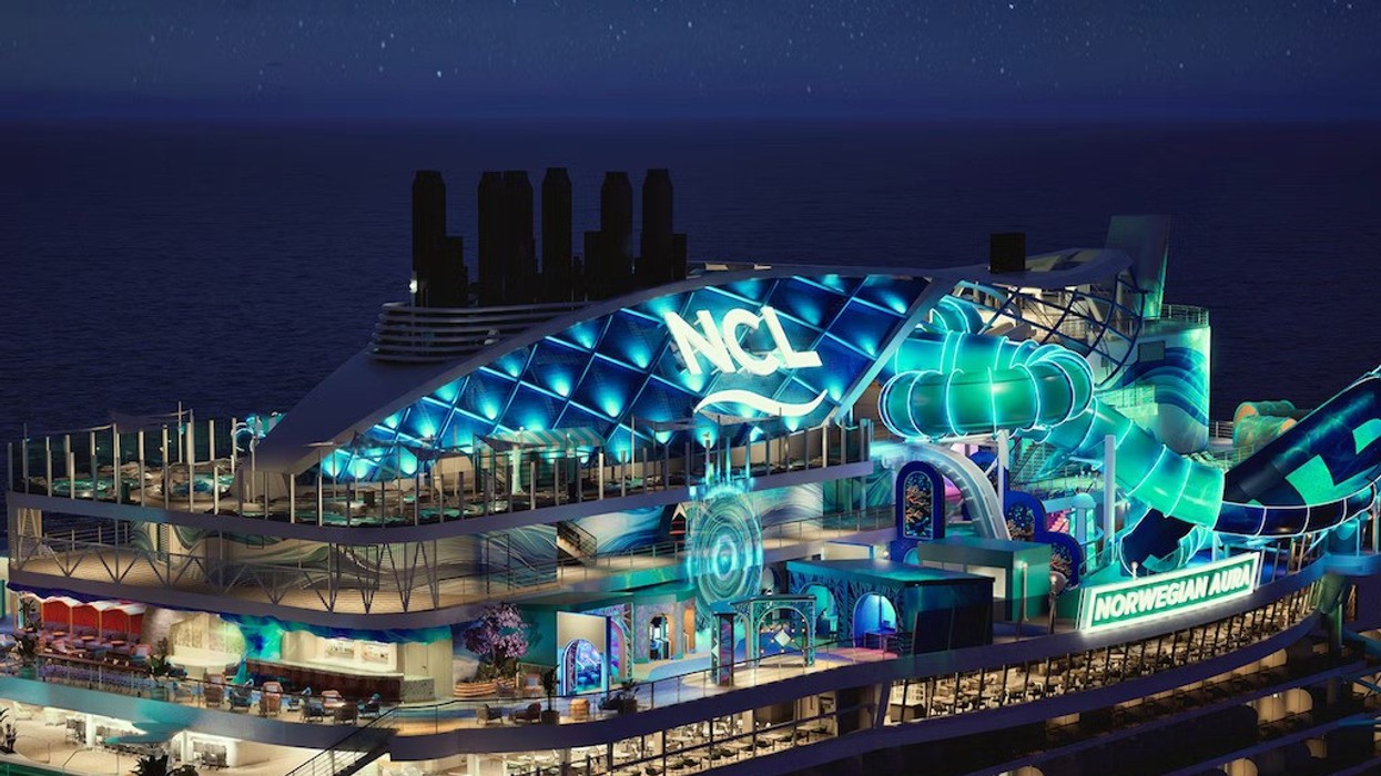 Illuminated cruise ship deck with slides and "NCL" sign at night, named "Norwegian Aura."