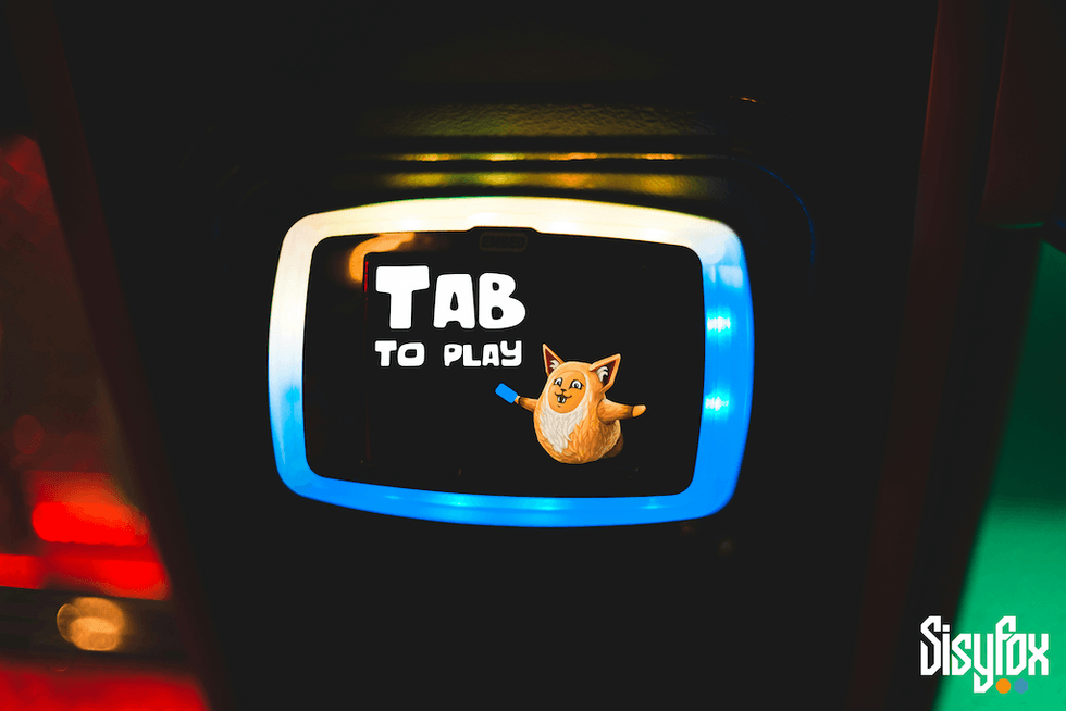 Illuminated display with "Tab to Play" message and cartoon fox graphic.