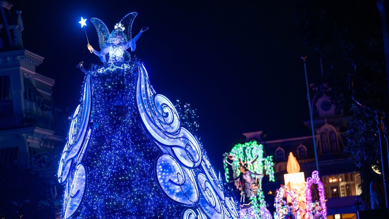 Illuminated fairy float with blue lights in a nighttime parade.