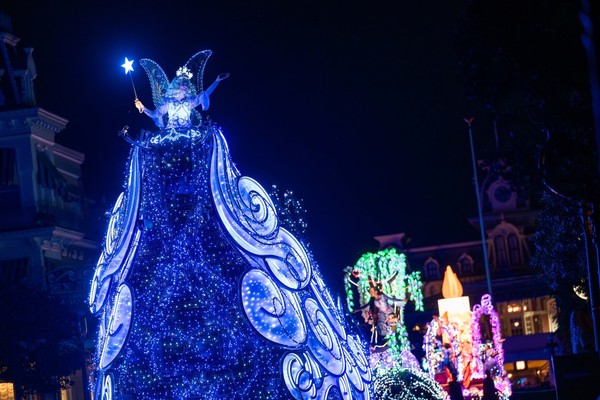 Illuminated fairy float with blue lights in a nighttime parade.