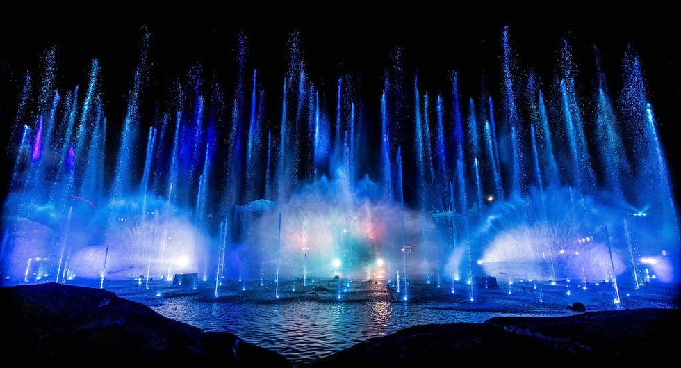 Illuminated fountains with blue and purple lights at night.