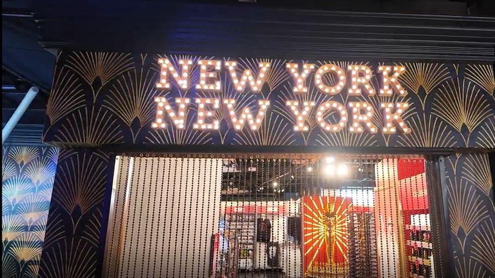 Illuminated "New York, New York" sign above a shop entrance with art deco patterns.