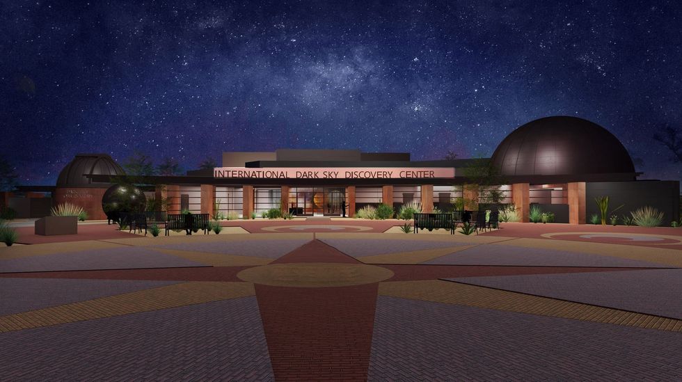 Illuminated observatory with domes under a starry night sky.